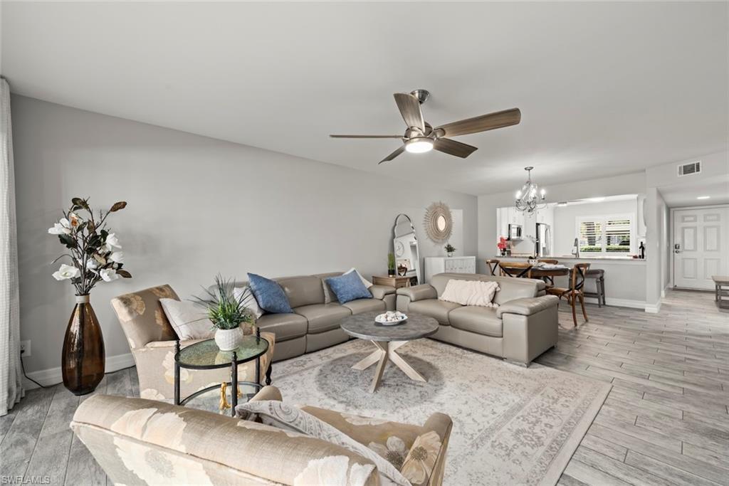 5965 Bloomfield Circle, Unit B104 Naples, FL 34112 - Photo 10 of 39 a living room with furniture a chandelier and a rug
