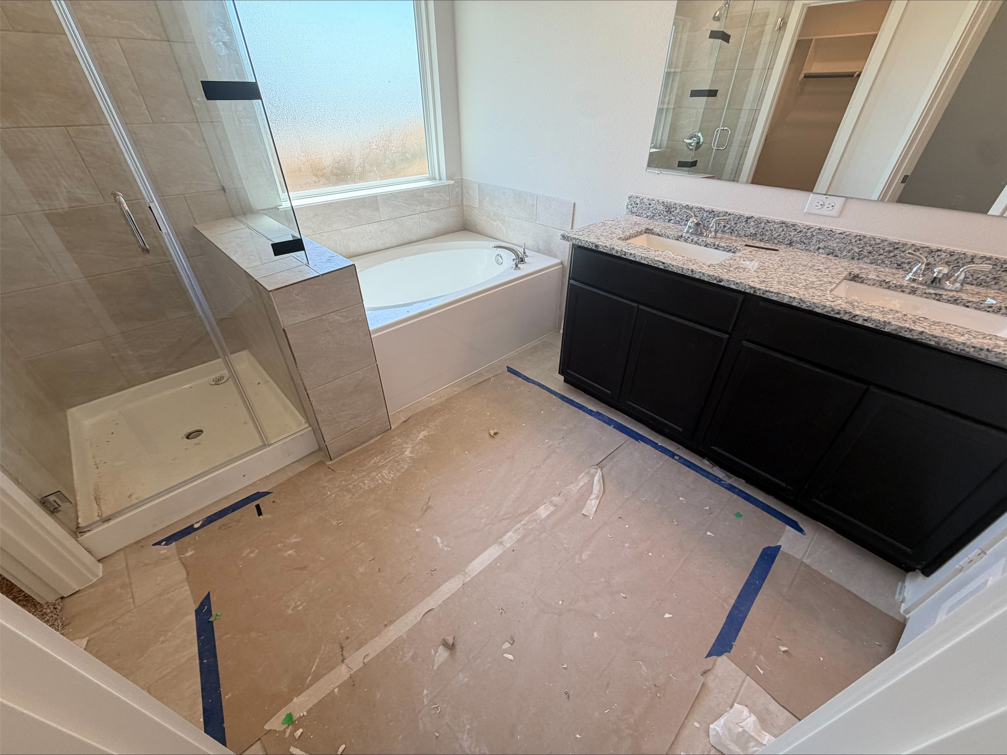 249 Lazy Lizzy Road Jarrell, TX 76537 - Photo 9 of 14 A spacious bathroom displays a dual-sink granite vanity alongside a built-in tub and separate glass-enclosed shower.