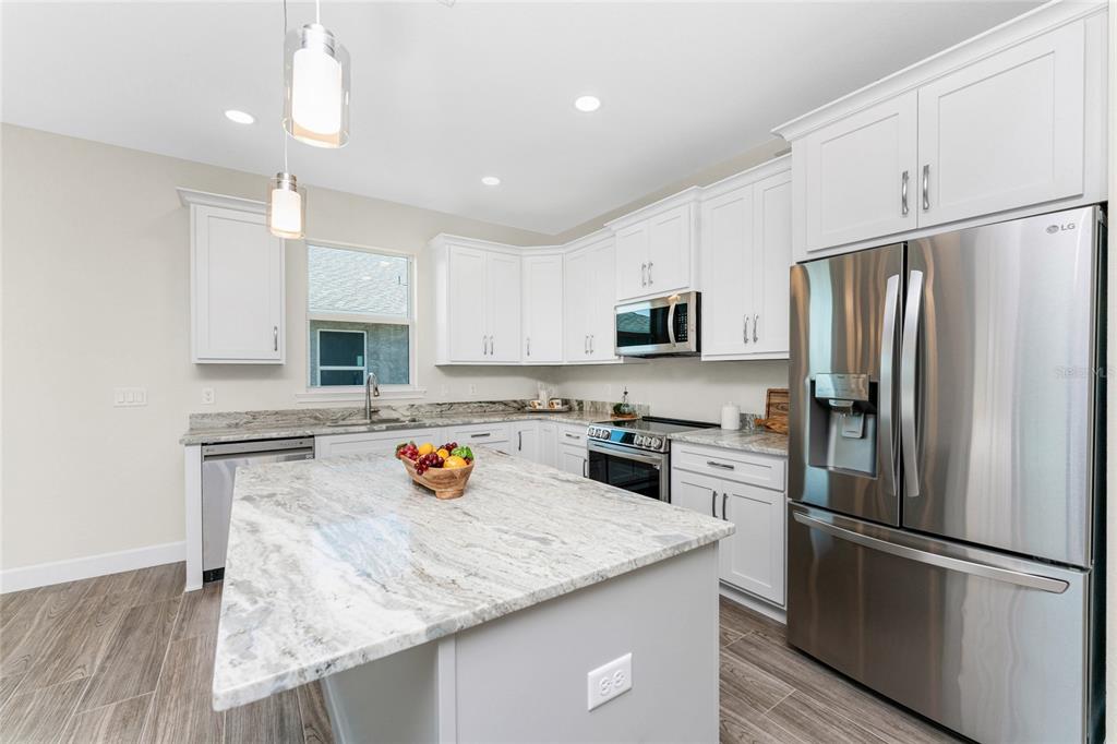 399 Sunset Road Rotonda West, FL 33947 - Photo 16 of 57 a kitchen with stainless steel appliances granite countertop a refrigerator a sink a stove a microwave and island