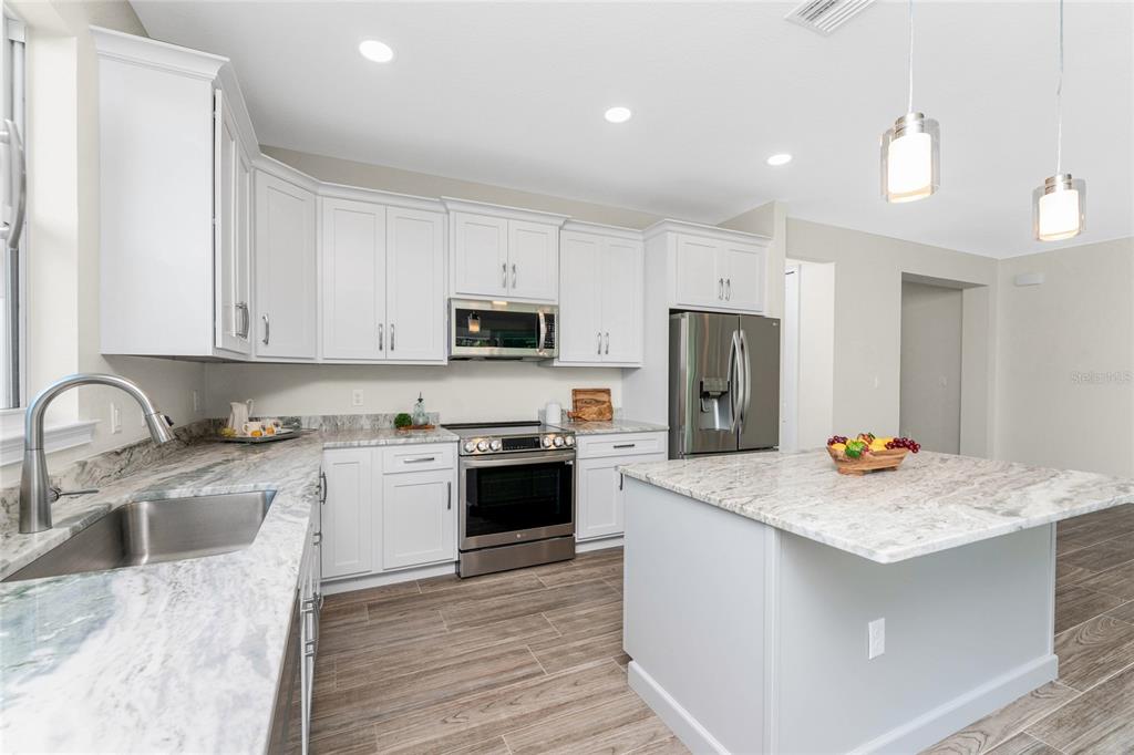 399 Sunset Road Rotonda West, FL 33947 - Photo 17 of 57 a kitchen with stainless steel appliances granite countertop a sink stove refrigerator and cabinets