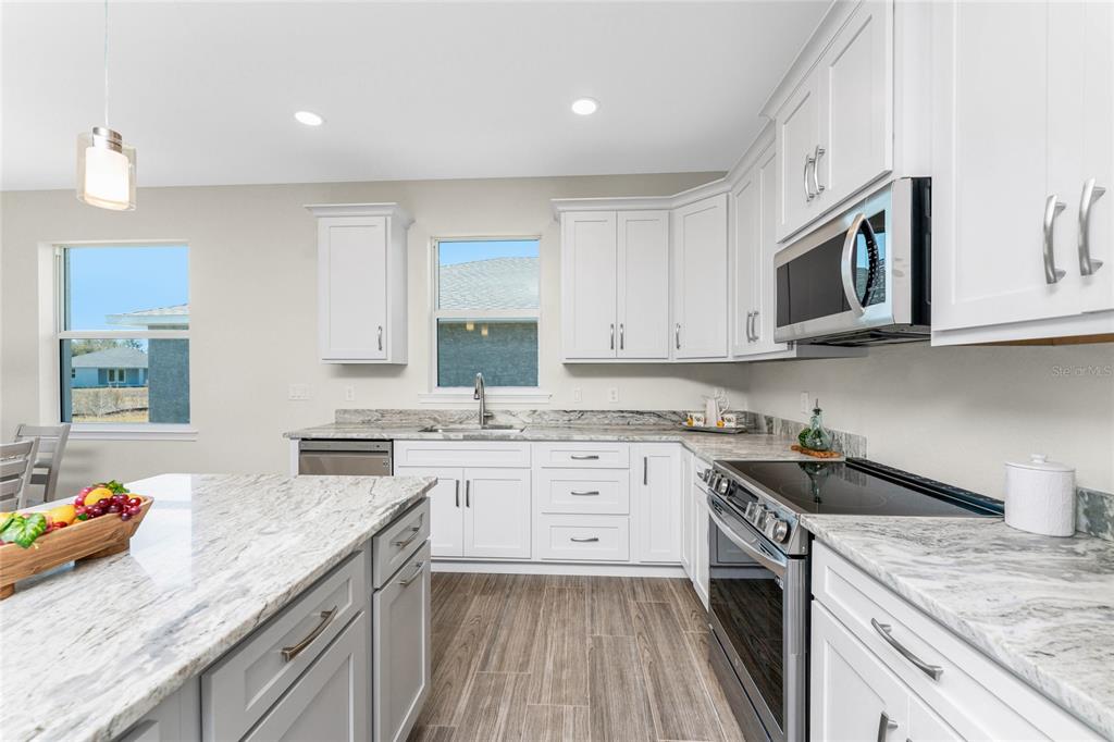 399 Sunset Road Rotonda West, FL 33947 - Photo 18 of 57 a kitchen with granite countertop cabinets stainless steel appliances a sink and wooden floor