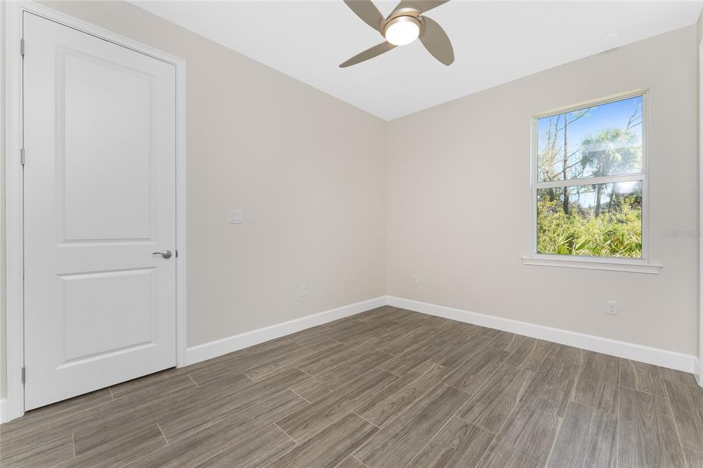 399 Sunset Road Rotonda West, FL 33947 - Photo 34 of 57 an empty room with wooden floor fan and windows