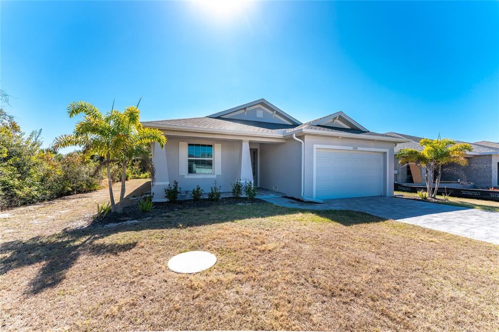 399 Sunset Road Rotonda West, FL 33947 - Photo 49 of 57 a front view of a house with a yard and garage