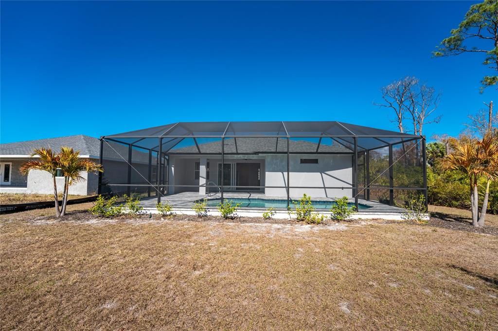 399 Sunset Road Rotonda West, FL 33947 - Photo 51 of 57 a backyard of a house with table and chairs under an umbrella