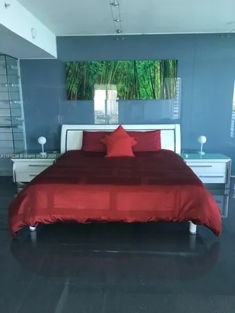 a large bed sitting in a bedroom next to a window