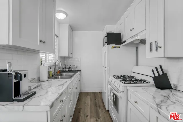 a kitchen with granite countertop a sink stove and refrigerator