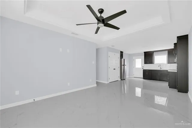 a view of a livingroom with a ceiling fan & kitchen space