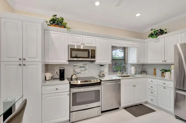 a kitchen with white cabinets stainless steel appliances and sink