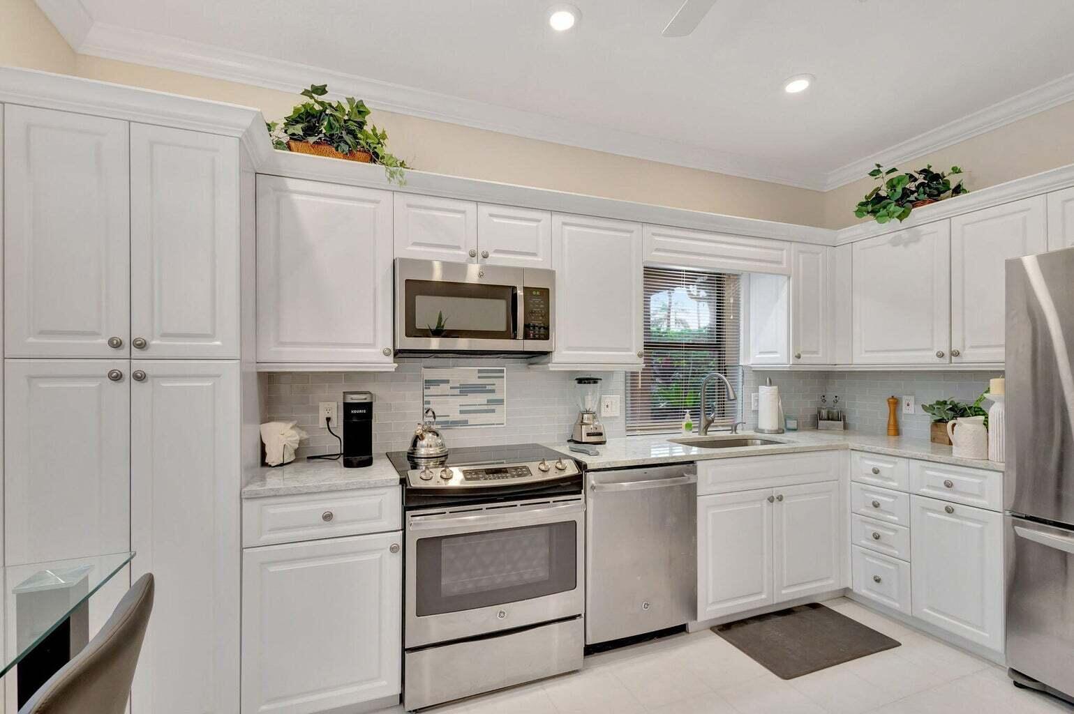 16151 West Bay Drive, Unit 161 Jupiter, FL 33477 - Photo 12 of 25 a kitchen with white cabinets stainless steel appliances and sink