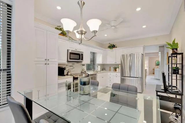 a kitchen with stainless steel appliances granite countertop a refrigerator a stove a microwave oven a sink dishwasher and white cabinets with wooden floor