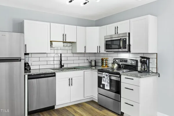 a kitchen with white cabinets and stainless steel appliances