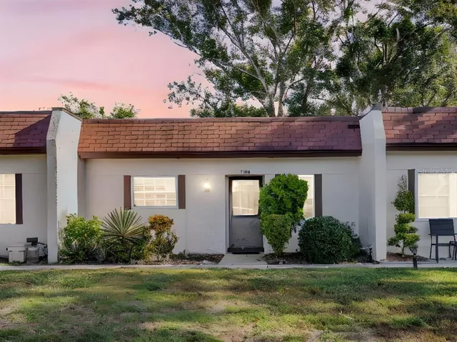 a view of a house with a yard plants and large tree