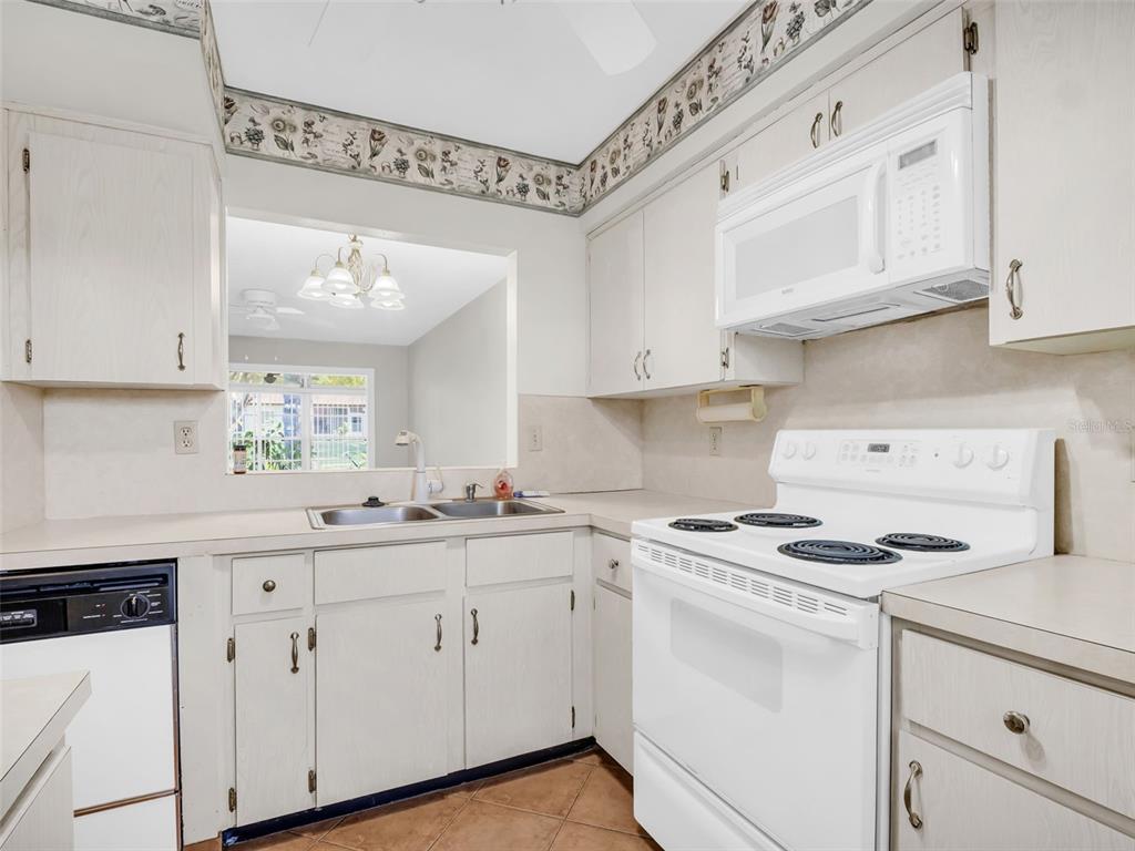 3109 Mission Grove Drive, Unit D Palm Harbor, FL 34684 - Photo 5 of 62 a kitchen with white cabinets white appliances sink and cabinets