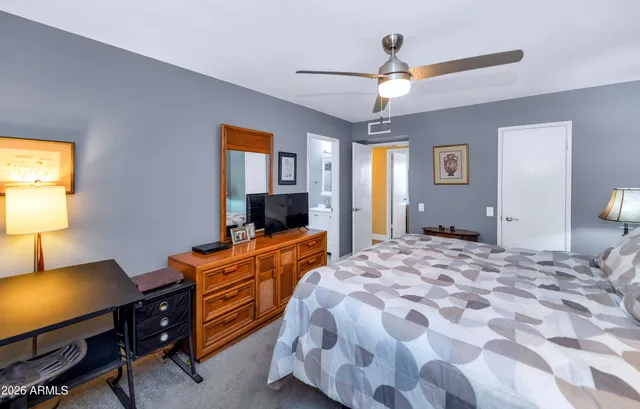 a bedroom with a bed and a flat tv screen on dresser