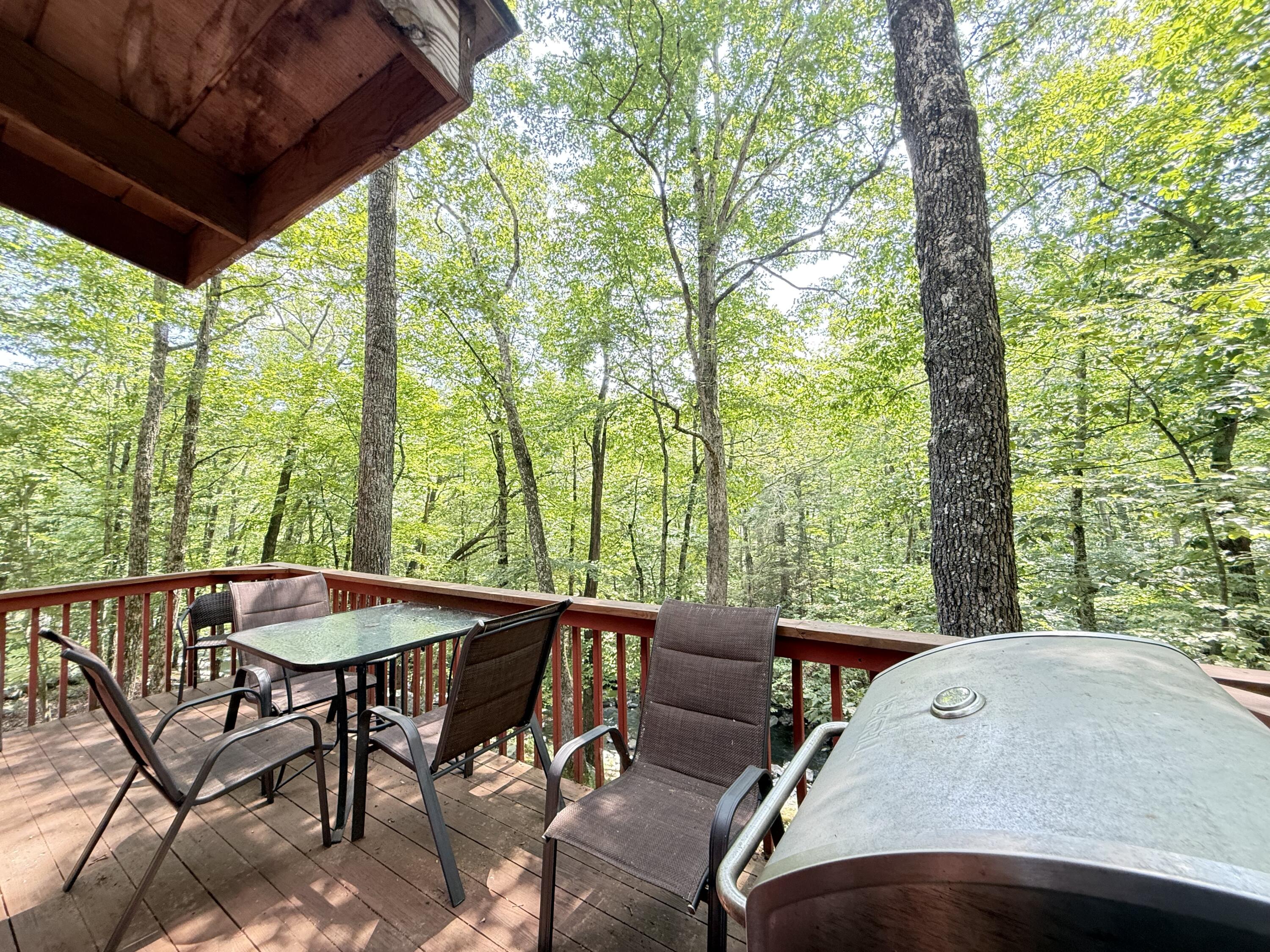 6414 Decker Road Bushkill, PA 18324 - Photo 32 of 65 a view of a patio with table and chairs under an umbrella with large trees
