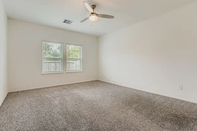 an empty room with closet and a ceiling fan