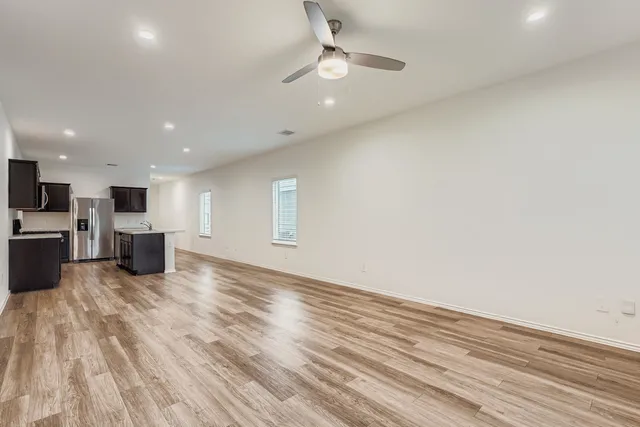 a view of an empty room with wooden floor and a window