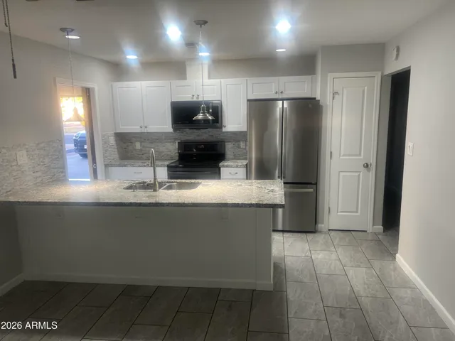 a view of a kitchen with kitchen island a sink stainless steel appliances and cabinets