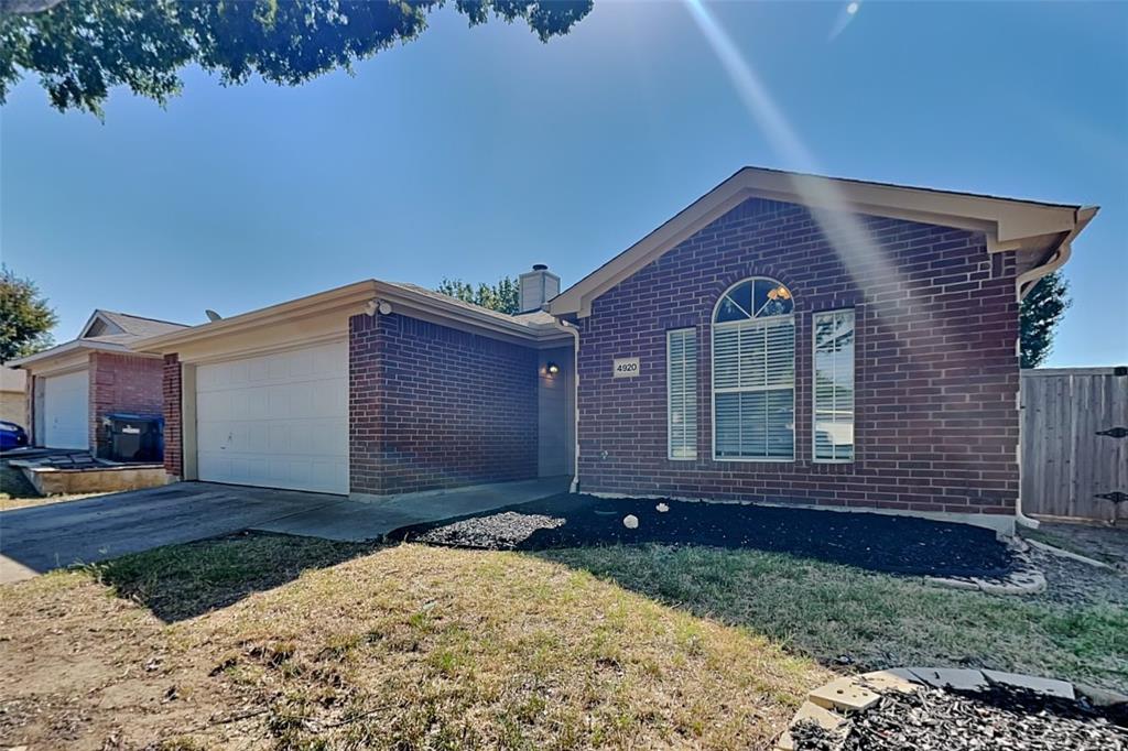 Ranch-style home with an attached garage, brick siding, concrete driveway, and a chimney
