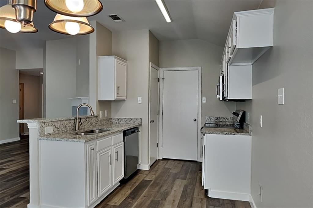 4920 Mountain Ridge Lane McKinney, TX 75071 - Photo 4 of 19 Kitchen featuring white cabinets, light stone countertops, dark wood finished floors, a peninsula, and lofted ceiling
