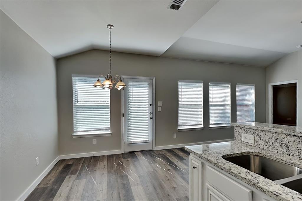 4920 Mountain Ridge Lane McKinney, TX 75071 - Photo 5 of 19 Kitchen with light stone countertops, vaulted ceiling, white cabinetry, dark wood-type flooring, and a chandelier