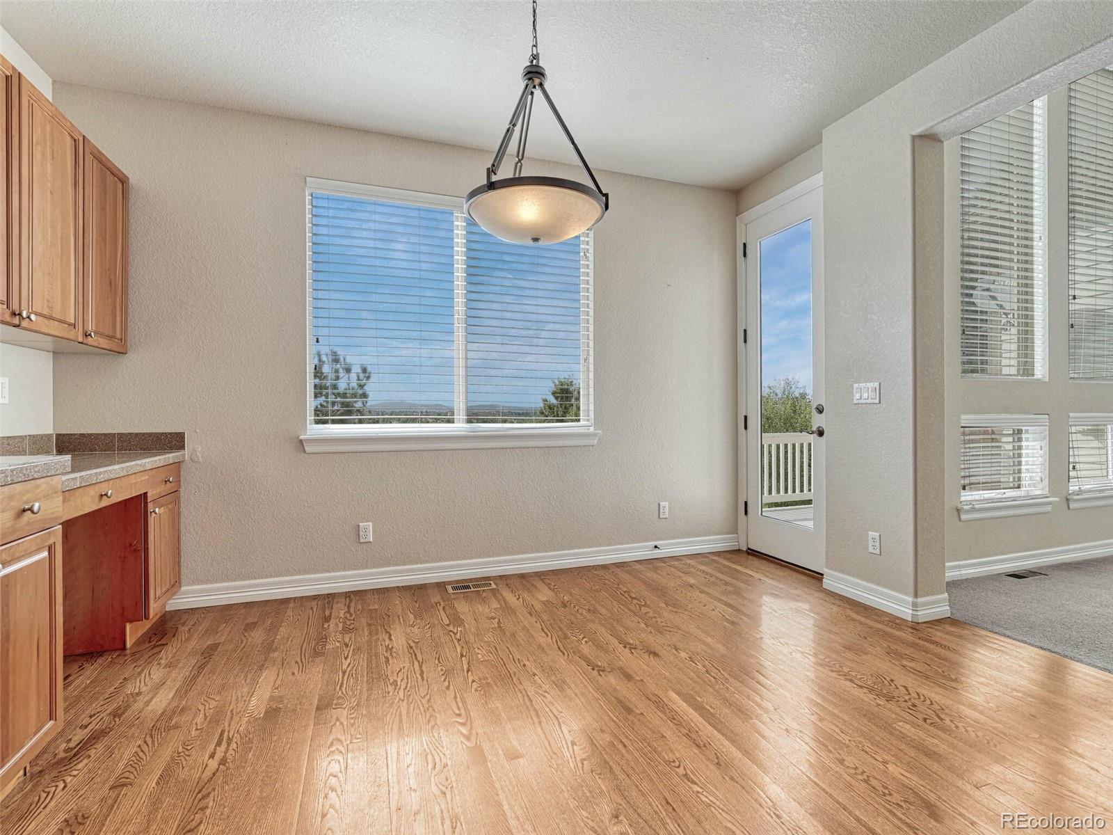 9741 Sunset Hill Circle Lone Tree, CO 80124 - Photo 11 of 43 a view of an empty room with wooden floor and a window