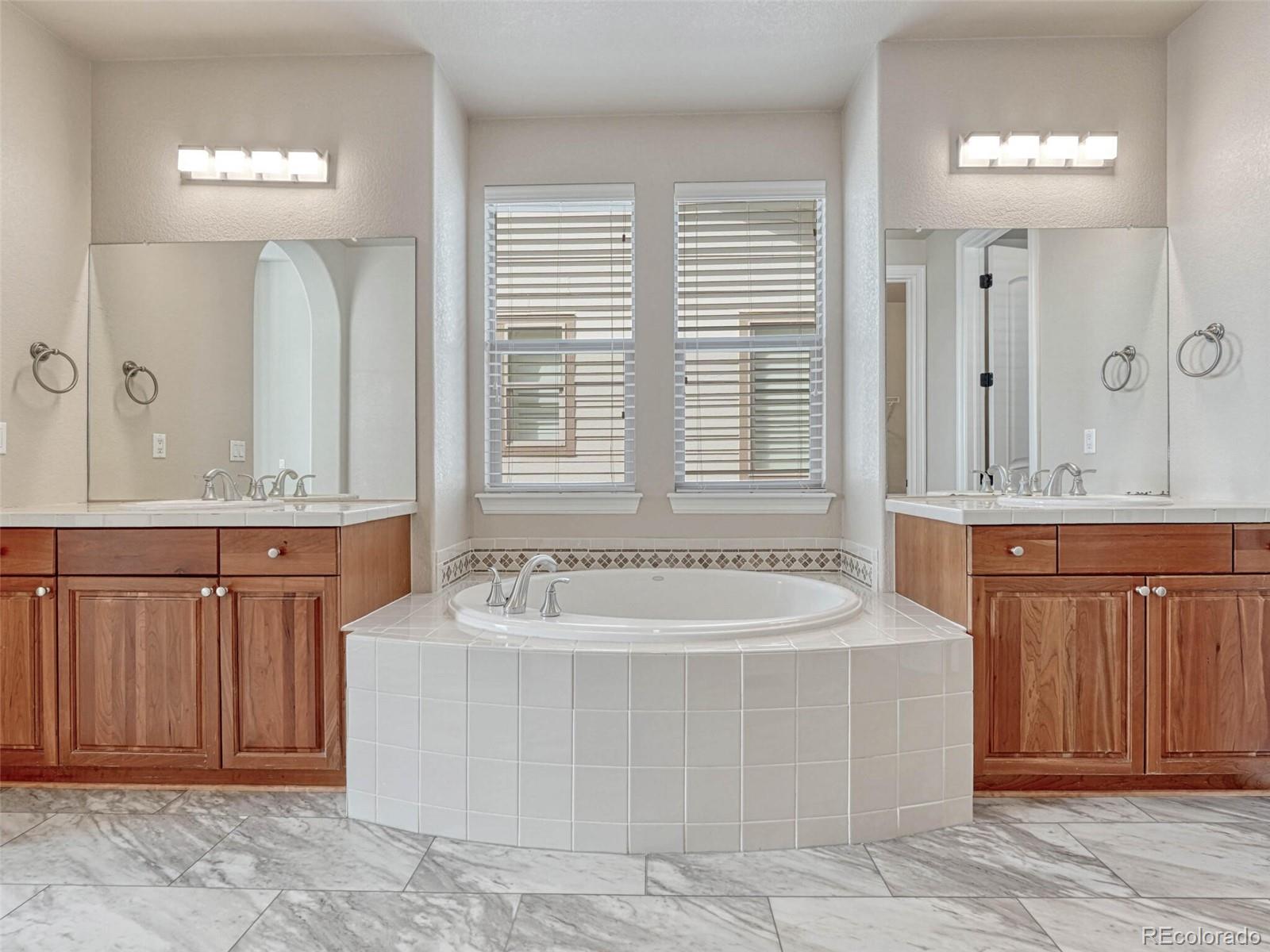 9741 Sunset Hill Circle Lone Tree, CO 80124 - Photo 25 of 43 a spacious bathroom with a tub a sink and mirror