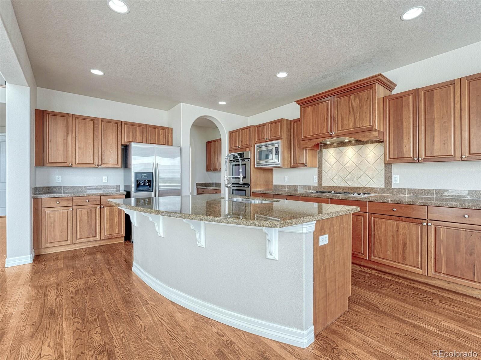9741 Sunset Hill Circle Lone Tree, CO 80124 - Photo 9 of 43 a kitchen with stainless steel appliances granite countertop a stove a sink and a refrigerator