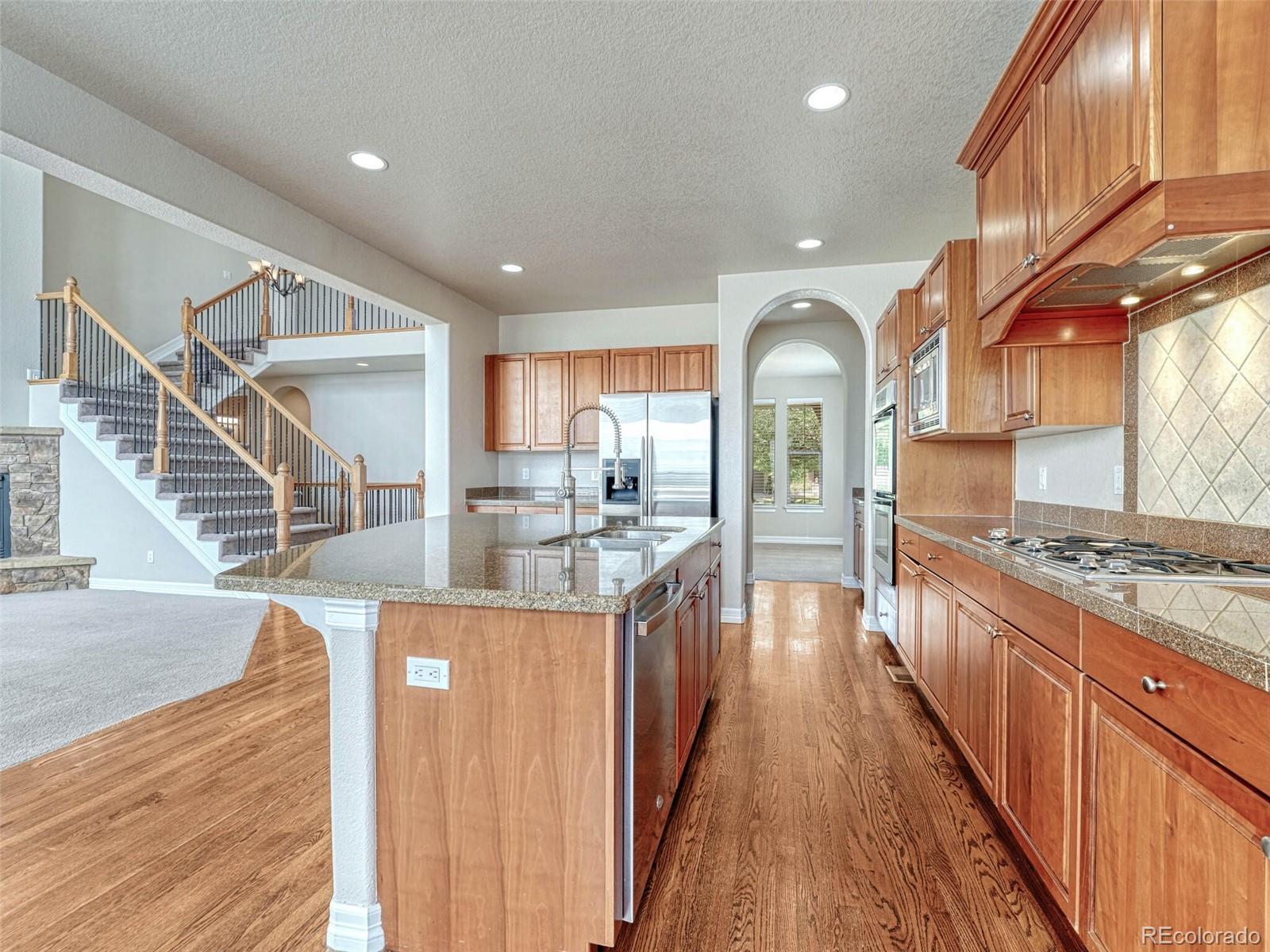 9741 Sunset Hill Circle Lone Tree, CO 80124 - Photo 10 of 43 a kitchen with stainless steel appliances granite countertop a stove and a wooden floors