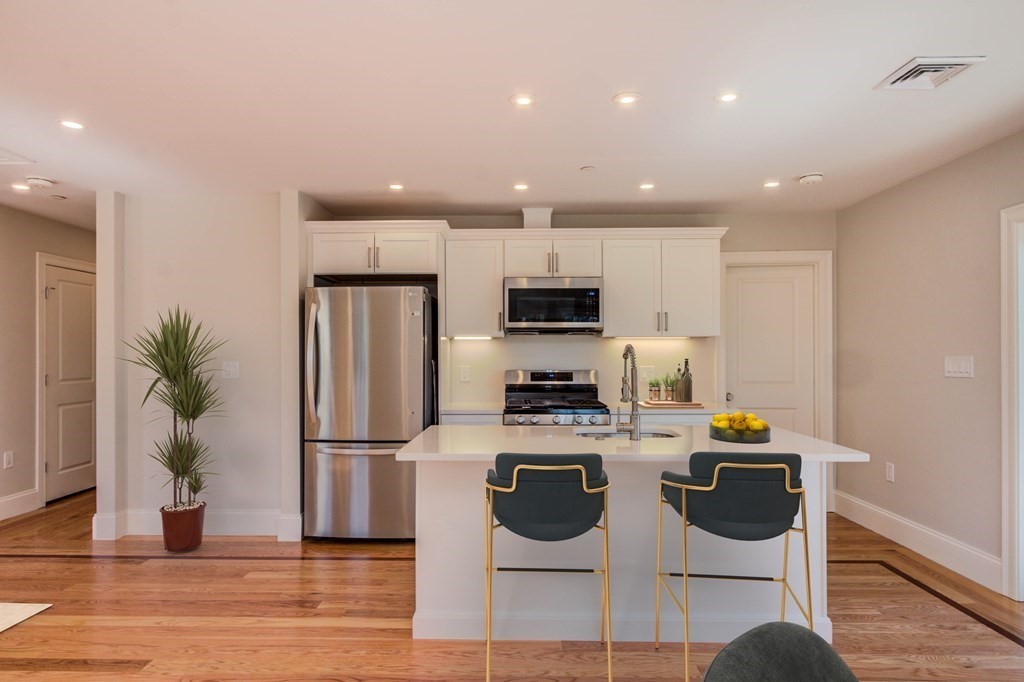 a kitchen with stainless steel appliances kitchen island granite countertop a refrigerator and a stove top oven