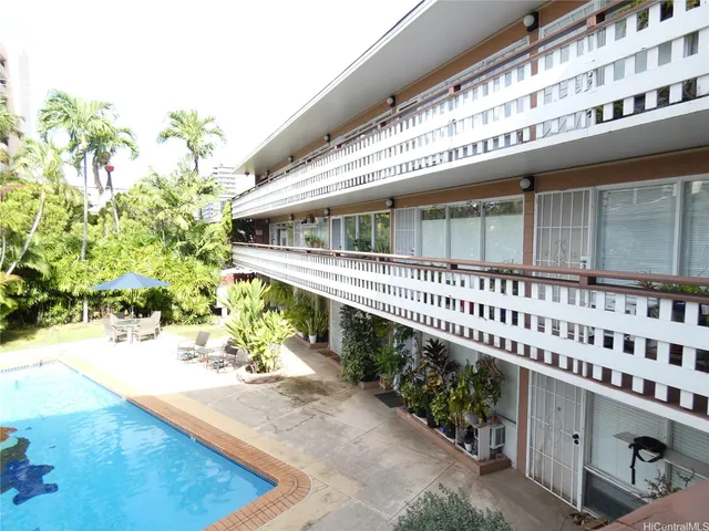 a large white building view with a garden space