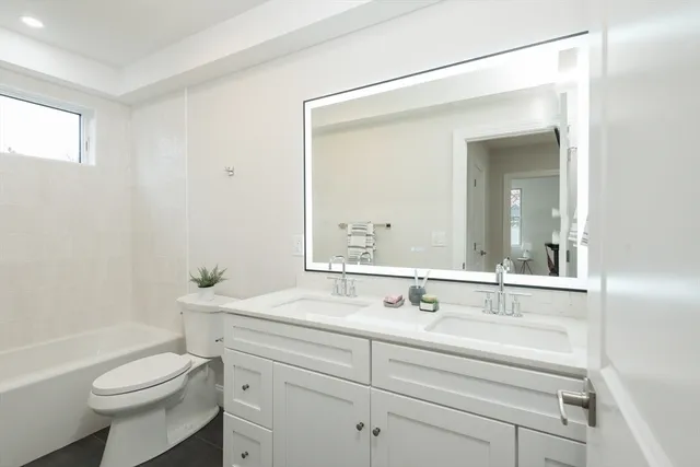 a bathroom with a toilet a sink a tub and mirror