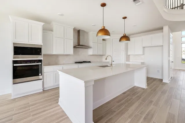 a kitchen with stainless steel appliances a sink a stove a microwave and wooden floor