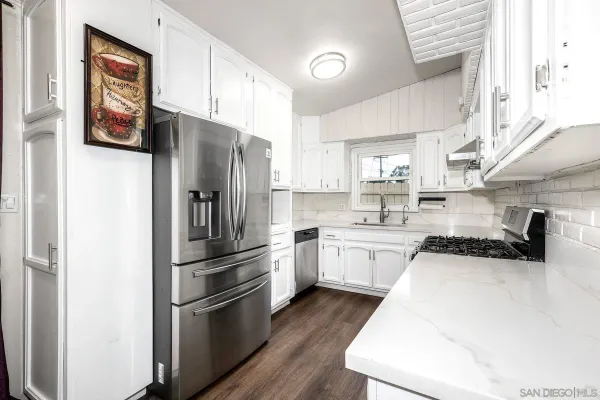 a kitchen with white cabinets and appliances
