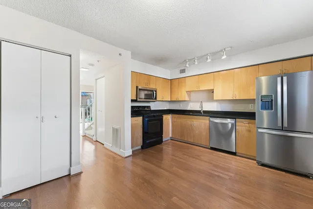 a kitchen with granite countertop a refrigerator and wooden floor