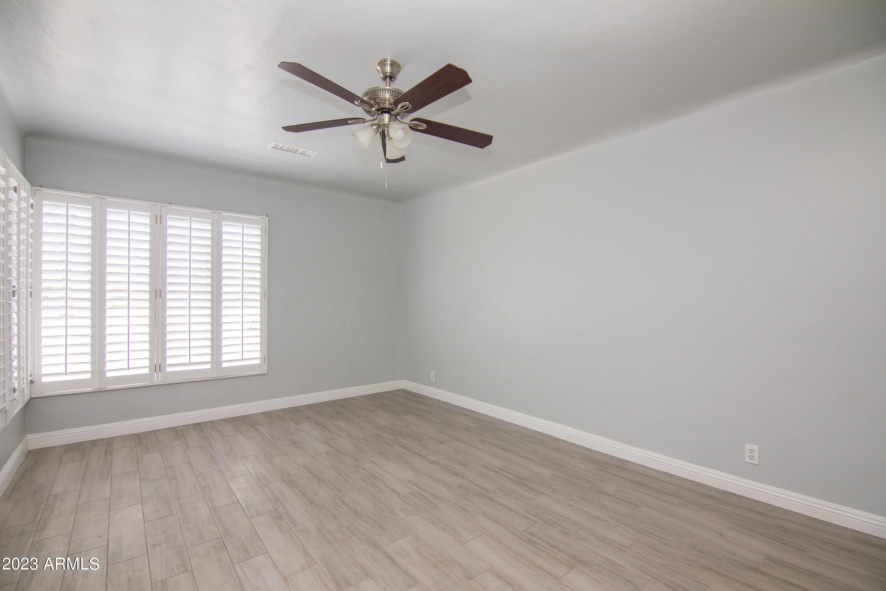 1318 East Granada Road Phoenix, AZ 85006 - Photo 8 of 38 an empty room with wooden floor fan and windows