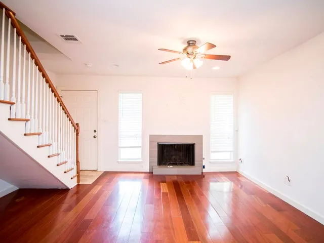 a view of an empty room with wooden floor and a fireplace
