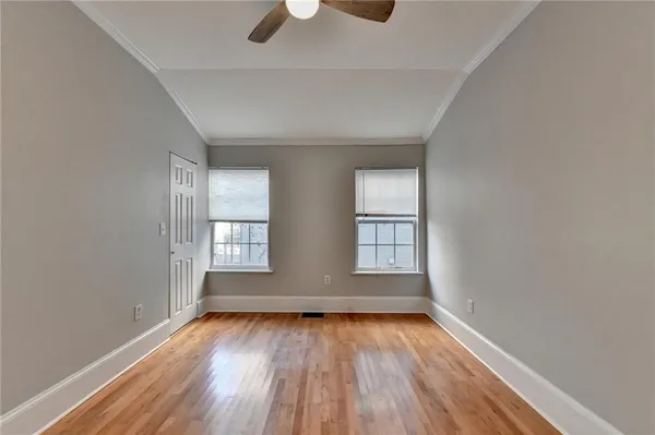 an empty room with wooden floor and windows