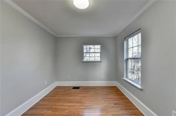 a view of an empty room with wooden floor and window