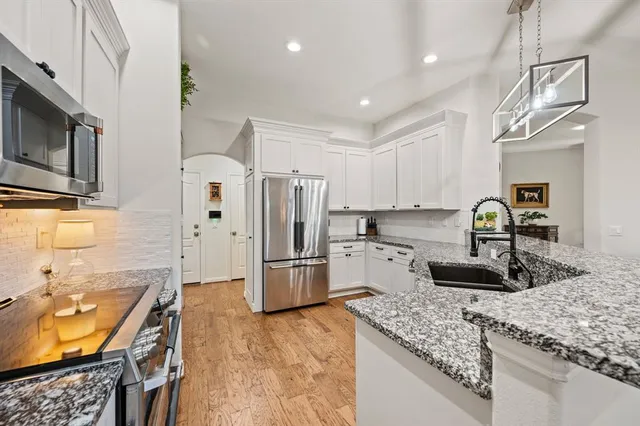 a kitchen with granite countertop a sink stove and refrigerator