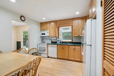 a kitchen with stainless steel appliances granite countertop a stove a sink dishwasher and a refrigerator with wooden floor