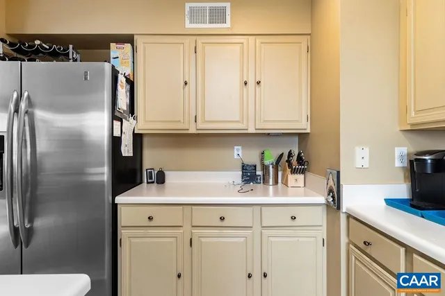 a kitchen with stainless steel appliances granite countertop a refrigerator a sink and white cabinets
