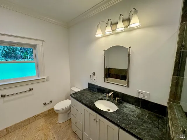 a spacious bathroom with a granite countertop sink mirror vanity and toilet