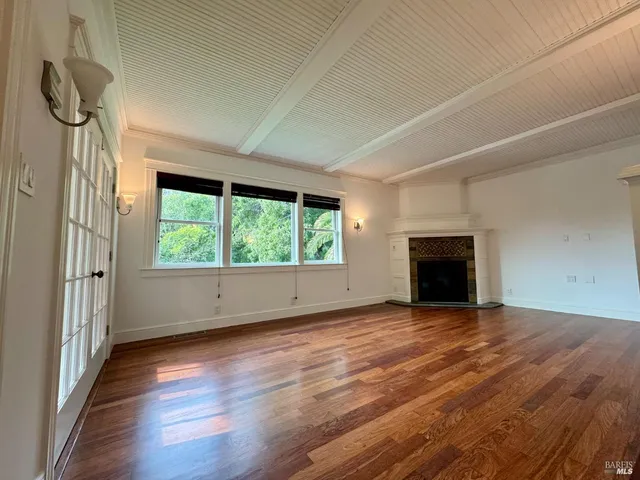 a view of empty room with wooden floor and fireplace