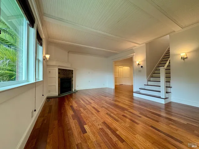 a view of a livingroom with wooden floor and staircase