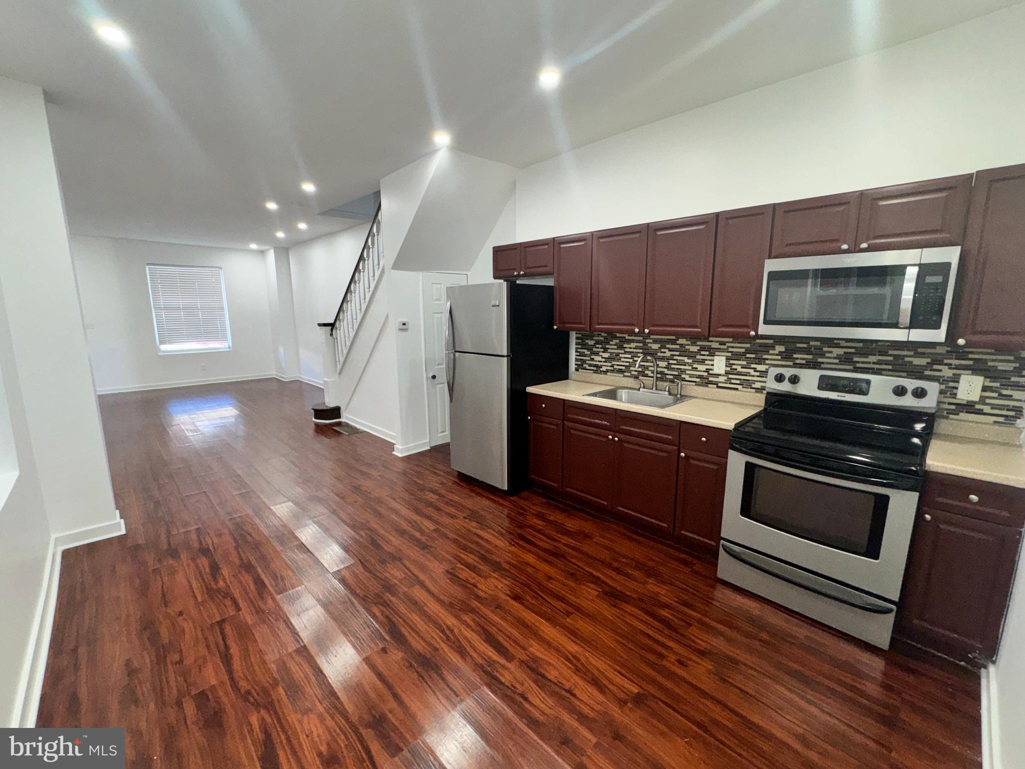 126 North Paxon Street Philadelphia, PA 19139 - Photo 11 of 38 a kitchen with stainless steel appliances wooden floors and wooden cabinets