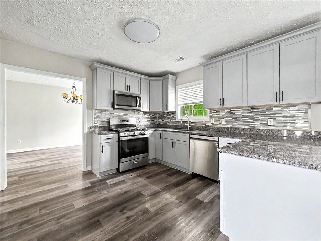 48 Savanna Court Powder Springs, GA 30127 - Photo 11 of 28 a kitchen with granite countertop a sink cabinets stainless steel appliances and a window