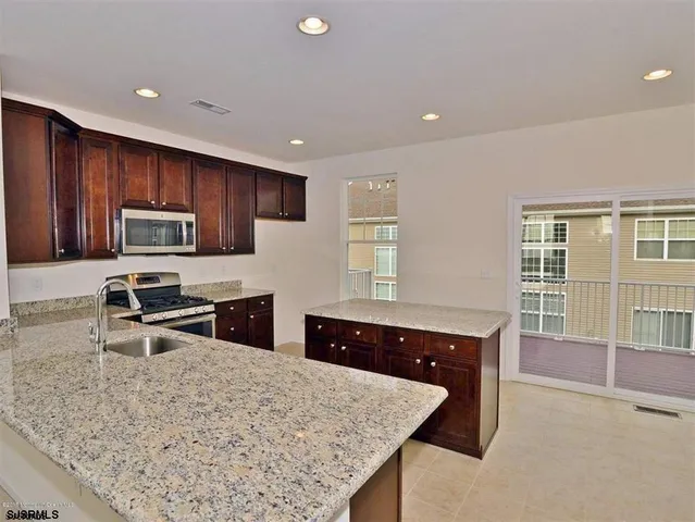 a kitchen with granite countertop wooden cabinets a counter top space and stainless steel appliances