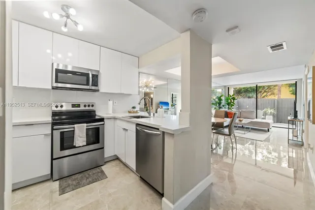 a kitchen with stainless steel appliances kitchen island granite countertop a stove top oven a sink a dining table and chairs