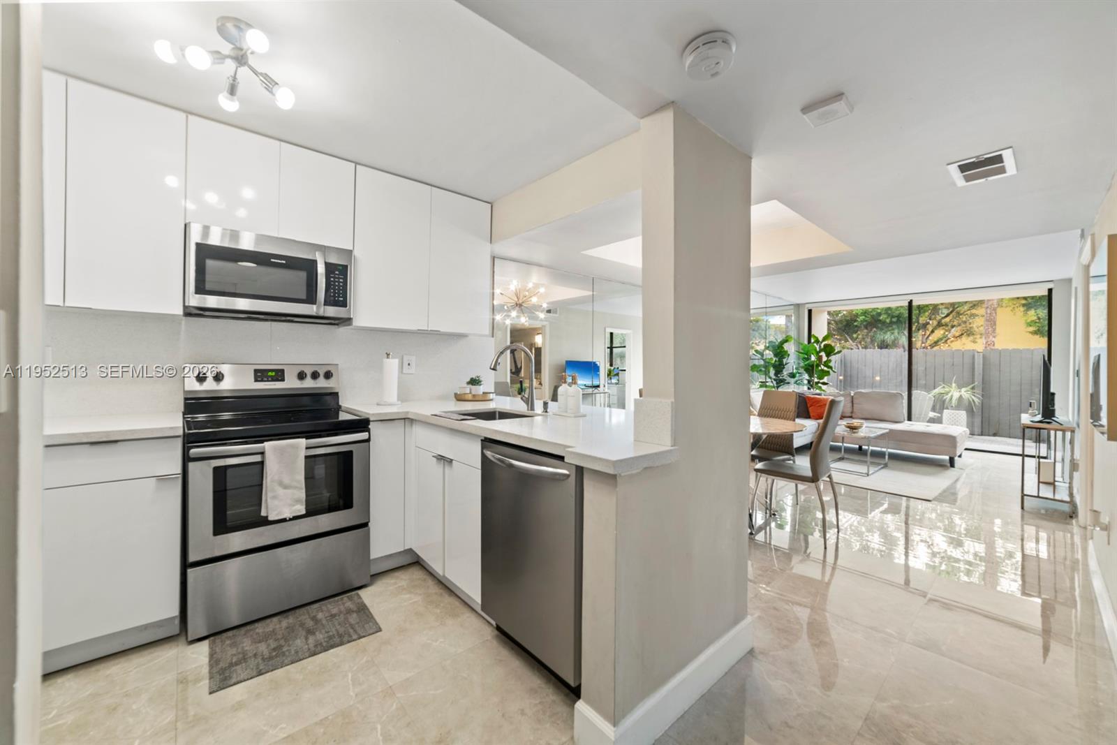 8002 Southwest 149th Avenue, Unit B118 Miami, FL 33193 - Photo 3 of 23 a kitchen with stainless steel appliances kitchen island granite countertop a stove top oven a sink a dining table and chairs